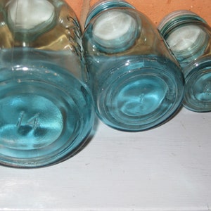 May include: Three blue glass jars with lids, the largest jar has the number "14" on the bottom.