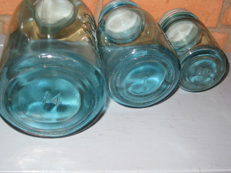 May include: Three blue glass jars with lids, the largest jar has the number "14" on the bottom.