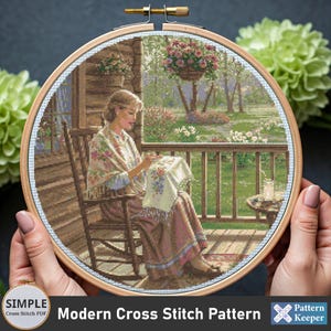 Puede incluir: Una mujer se sienta en una mecedora en un porche, cosiendo un trozo de tela. Lleva una chalina con estampado floral y una falda larga. El porche tiene una barandilla y vistas a un césped verde con flores. La escena está enmarcada en un aro de madera.