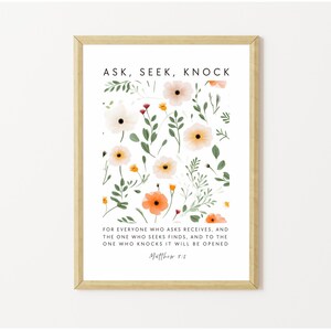May include: A framed print with the words "ASK, SEEK, KNOCK" at the top. The print features a floral design with white, peach, and orange flowers and green leaves. The text "FOR EVERYONE WHO ASKS RECEIVES..." is at the bottom.