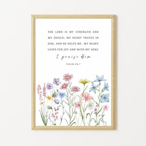 May include: Framed print featuring a floral watercolor design and the text "THE LORD IS MY STRENGTH AND MY SHIELD, MY HEART TRUSTS IN HIM, AND HE HELPS ME. MY HEART LEAPS FOR JOY AND WITH MY SONG I praise Him PSALM 28:7." The frame is a light gold color.