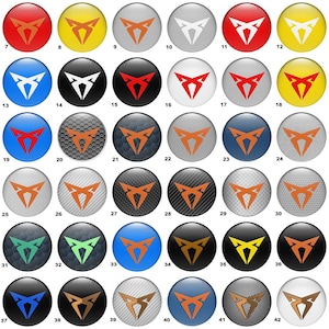 May include: A white ceramic mug with a black handle and the text "But First, Coffee" in a bold, black font. The mug is set against a blurred background, suggesting a cozy setting.