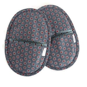 May include: A pair of oval-shaped fabric pot holders featuring a dark blue background with a repeating pattern of small red and white floral motifs. Each pot holder has a horizontal pocket opening across the center and a small white brand label.