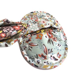 May include: A light blue eye mask with a floral pattern in shades of pink, orange, brown, and yellow. The mask is made of fabric and has a soft, comfortable feel.