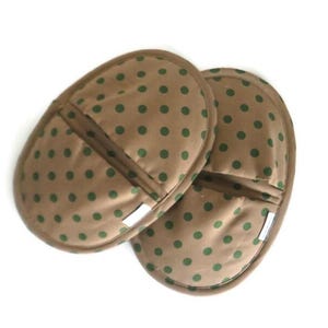 May include: Two brown oven mitts with green polka dots. The mitts have a pocket on the back side.