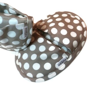 May include: Two brown fabric baby shoes with white polka dots. The shoes have a white label with the text "Made by Sydney" on them.