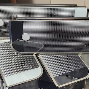 Puede incluir: Cuatro cubiertas de cocina negras y plateadas con un patrón de rejilla. Las cubiertas son de vidrio y tienen un borde redondeado.