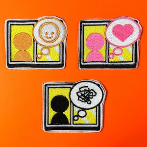 Puede incluir: Tres parches bordados con marcos rectangulares sobre fondo amarillo. Uno muestra una figura naranja con una burbuja de pensamiento sonriente, otro una figura rosa con un corazón y el tercero una figura negra con un garabato en la burbuja.