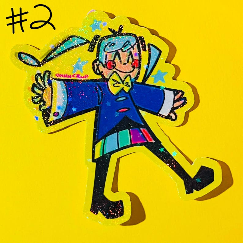 May include: A colorful sticker featuring a cartoon character with light blue hair, a yellow bow tie, and a blue jacket. The character has a rainbow-colored panel on the lower part of the jacket. The sticker is outlined in glitter and has a yellow background with the number "#2" in the top left corner.