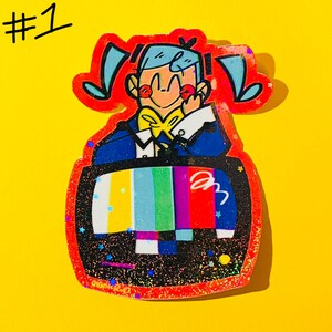 May include: A colorful pin featuring a cartoon character with blue hair and a yellow bow tie, set against a television screen displaying a test pattern. The pin has a red outline and the number "#1" in the upper left corner.