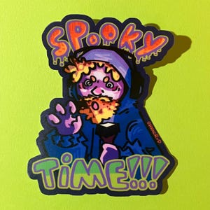 May include: A sticker with a cartoon illustration of a person in a blue hoodie with a beard. The sticker has the words "Spooky Time!!!" in orange and green. The background is lime green.