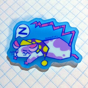 May include: A cartoon-style sticker featuring a sleeping mouse wearing a yellow and purple polka-dot nightcap. The mouse is white with purple spots and pink ears. A blue speech bubble with a white "Z" is above the mouse. The sticker has a blue outline.
