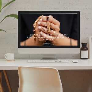 May include: A desktop computer displays a close-up of hands holding a wooden cross and rosary beads. The screen features the word "WORK" and the text "DO NOT WORRY ABOUT TOMORROW. FOR TOMORROW WILL WORRY ABOUT ITSELF" and "MATTHEW 6:34".
