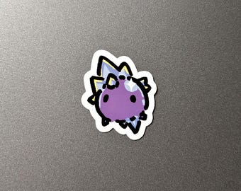 May include: A sticker featuring a cartoonish purple creature with spiky, crystal-like protrusions. The creature has a round body, two small black eyes, and a white outline. The crystals are light blue and yellow.