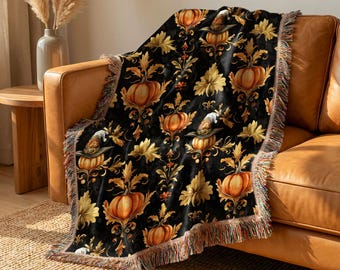 May include: A black woven throw blanket featuring a repeating pattern of orange pumpkins, some wearing pointed hats, interspersed with golden yellow foliage and ornate scrollwork. The blanket has a fringed edge with multicolored threads.