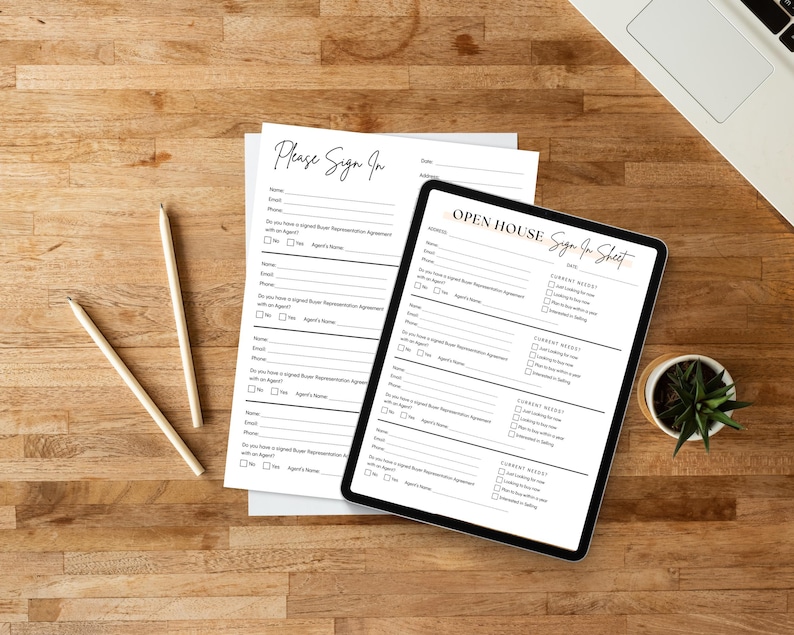 May include: An open house sign-in sheet on a tablet and a paper form, with the text "Please Sign In" and "Open House Sign In Sheet". Two pencils and a small potted plant are also on the wooden surface.