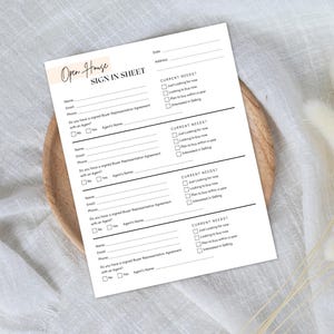 May include: A white Open House Sign In Sheet with black text, including fields for name, email, and phone. The sheet also includes checkboxes for current needs and buyer representation agreement. The sheet is on a wooden plate.