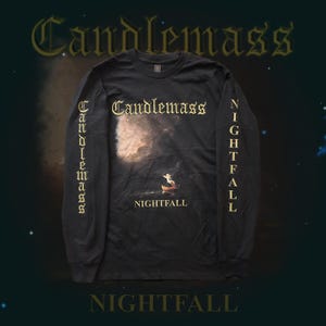 Może przedstawiać: Czarna koszulka z długim rękawem z nazwą zespołu "Candlemass" złotymi literami na piersi. Koszulka przedstawia grafikę sceny niebieskiej z napisem "NIGHTFALL" poniżej. Nazwa zespołu jest również wydrukowana pionowo na lewym rękawie i "NIGHTFALL" na prawym rękawie.