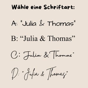 May include: A beige background displays text in black, including "W&auml;hle eine Schriftart:" and four options labeled A through D. Each option showcases "Julia & Thomas" in a different font style, offering a selection of typography choices.