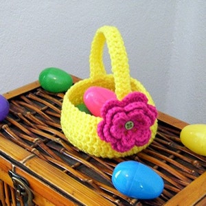 May include: A yellow crocheted Easter basket with a pink crocheted flower and a green button in the center. The basket is filled with plastic Easter eggs in pink, blue, and green.