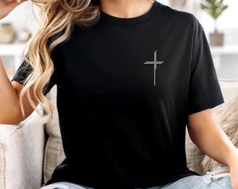 Può includere: T-shirt nero con un design a croce bianca minimalista. La maglietta a maniche corte è realizzata in un materiale morbido. Un design semplice ed elegante per l'uso quotidiano.
