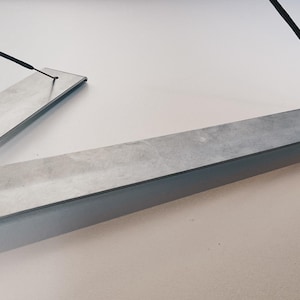 May include: Two silver metal incense holders with a black incense stick resting on one of the holders.