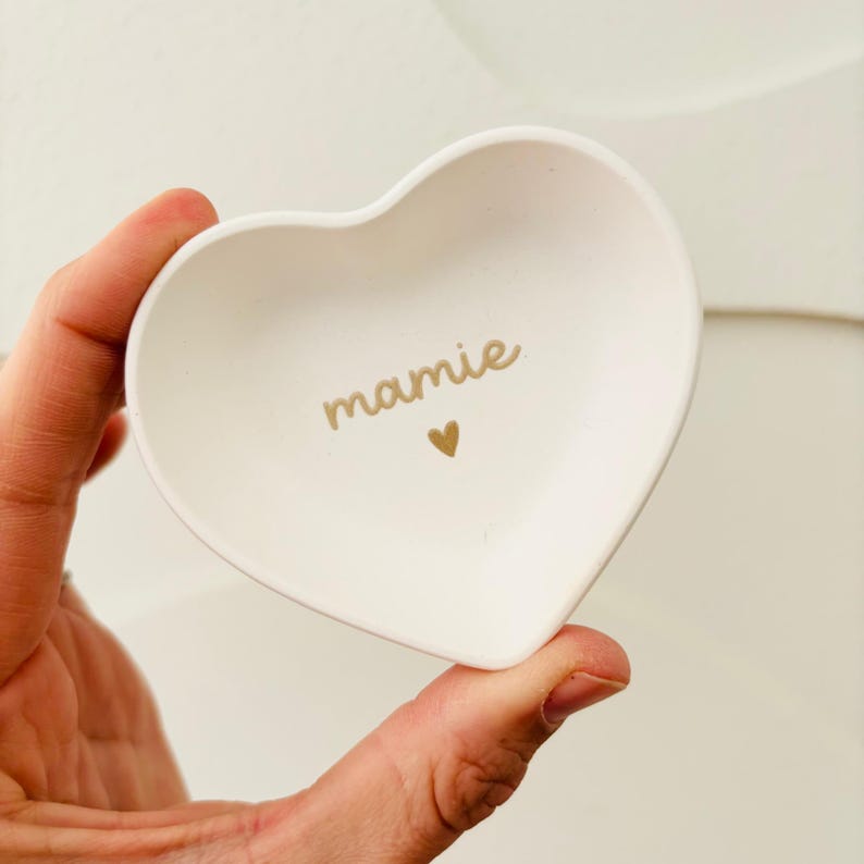 Może przedstawiać: Biała ceramiczna miseczka w kształcie serca z napisem "mamie" w złotych literach i małym złotym sercem.