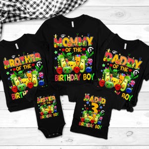 May include: Black t-shirts and a onesie with colorful birthday-themed graphics. The shirts read "Mommy", "Daddy", "Brother", and "Sister" with fruit and vegetable illustrations. One shirt says "David 3 Birthday Boy".