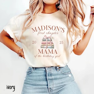 May include: Ivory-colored t-shirt with the text "MADISON'S first chapter" above a stack of books tied with a pink ribbon. Below the books, the text reads "MAMA of the birthday girl". The numbers "20" and "25" flank the book stack.