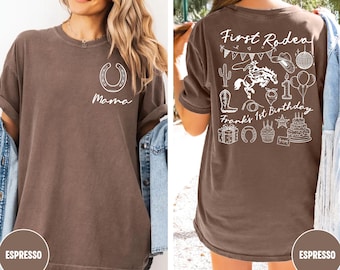 May include: Espresso-colored t-shirt with a horseshoe and the word "Mama" on the front. The back features a "First Rodeo" design with a cowboy on a horse, balloons, and the text "Frank's 1st Birthday."