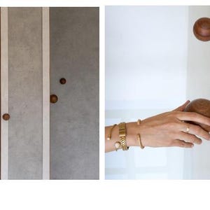 May include: Wooden cabinet door knobs in a warm brown tone. The knobs are round and have a smooth finish. The image also shows a set of gray cabinet doors with matching knobs and a white door with a knob.