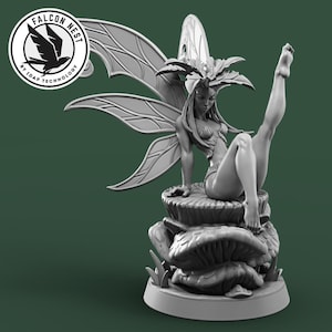 Peut inclure: Une figurine grise et détaillée d'une fée avec des ailes, assise sur un champignon. La fée a de longs cheveux, une couronne de feuilles et porte une petite tenue de feuilles. La figurine est sur une base ronde.