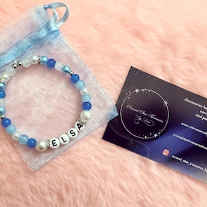 May include: A white ceramic mug with a black handle and the text "But First, Coffee" in a bold, black font. The mug is set against a blurred background, suggesting a cosy setting.