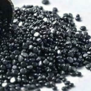 May include: A close-up shot of a pile of small, dark, rounded objects, possibly beads or pellets, spilling from a container. The objects are a deep, glossy black, creating a contrast against the white background.