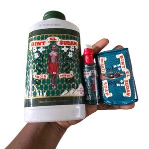 Puede incluir: Una colección de productos Bint El Sudan, que incluye un gran recipiente de talco, dos botellas pequeñas y una pastilla de jabón. El embalaje presenta un diseño verde y blanco con el nombre de la marca y un gráfico de una mujer. La pastilla de jabón está envuelta en azul.