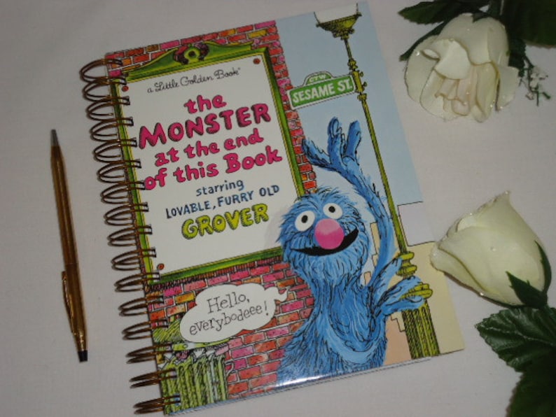 May include: A spiral-bound notebook featuring the cover of the Little Golden Book titled The Monster at the End of This Book, starring lovable, furry old Grover. The cover shows a blue monster, a brick wall, and the text Hello, everybodeee!
