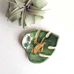 Green Monstera leaf shaped ceramic bowl, used as a jewelry dish to hold necklace and rings.