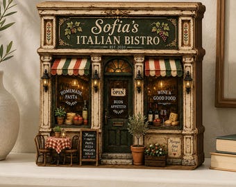 May include: A miniature model of Sofia's Italian Bistro with a distressed cream frame, green signage, and striped awnings. The storefront features illuminated windows displaying pasta, wine, and food, with a small table, chairs, and potted plants.