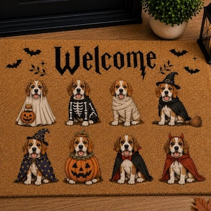 May include: A rectangular tan doormat featuring the word Welcome in black text and eight beagle dogs dressed in various Halloween costumes, including a ghost, skeleton, mummy, witch, pumpkin, vampire, and devil, accented by black bat silhouettes.