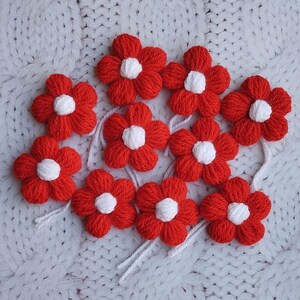 Puede incluir: Diez flores de lana roja con centros blancos. Las flores están hechas a mano y tienen un encanto simple y rústico.