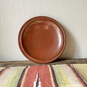 May include: A white ceramic mug with a black handle and the text "But First, Coffee" in a black, bold font. The mug is on a white surface.