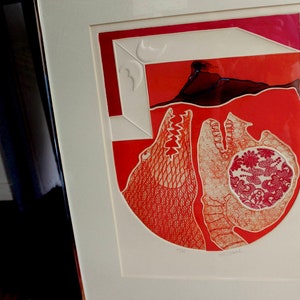May include: Framed abstract art print with a red and white color scheme. The artwork features geometric shapes and stylized figures, with a central design of a floral pattern. The print is encased in a white mat and a silver frame.