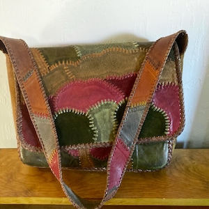 May include: A patchwork leather shoulder bag with a flap closure. The bag features a variety of colors, including red, green, brown, and orange, stitched together. The strap is made of the same patchwork leather.