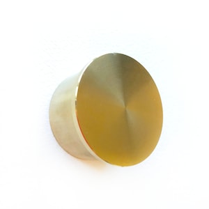 May include: A gold-colored metal knob with a smooth, round surface.