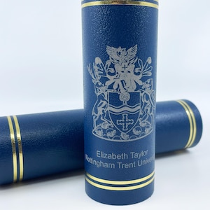 May include: Two navy blue cylindrical cases with gold trim. One case is upright, displaying a detailed silver crest and the text "Elizabeth Taylor Nottingham Trent Unive". The second case is horizontal.
