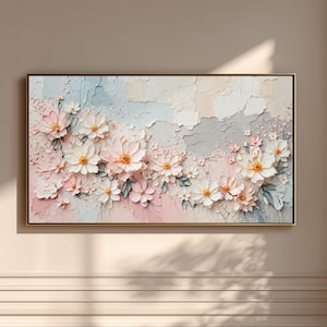 May include: A framed floral art piece featuring a textured, layered design. The artwork showcases white and peach-colored flowers with green leaves against a backdrop of pastel pink, blue, and gray hues. The frame is a thin, dark color.