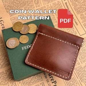 Puede incluir: Un monedero de cuero marrón con costuras blancas, junto a un libro verde y varias monedas. El texto "COIN WALLET PATTERN" se muestra encima del monedero. Un icono PDF rojo está en la esquina superior derecha.