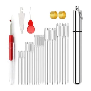 Op de afbeelding: Een naaikit met diverse gereedschappen. Bevat een naadontrafelaar met een rode handgreep, een naaldinrijger, twee vingerhoeden en een zilveren naaldenkoker. Er zijn meerdere maten naalden.