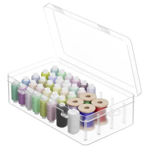 Könnte beinhalten: Eine rechteckige Aufbewahrungsbox aus durchsichtigem Kunststoff mit Klappdeckel, die mehrere Nähgarnrollen in verschiedenen Farben enthält. Die Garnrollen sind in Reihen angeordnet, einige davon mit hölzernen Enden und weißen Kappen.