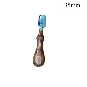 May include: A 35mm (1.38 inches) long, hand-held tool with a polished metal blade and a wooden handle. The handle is a dark brown color with a curved, ergonomic design. The blade is a shiny silver color.